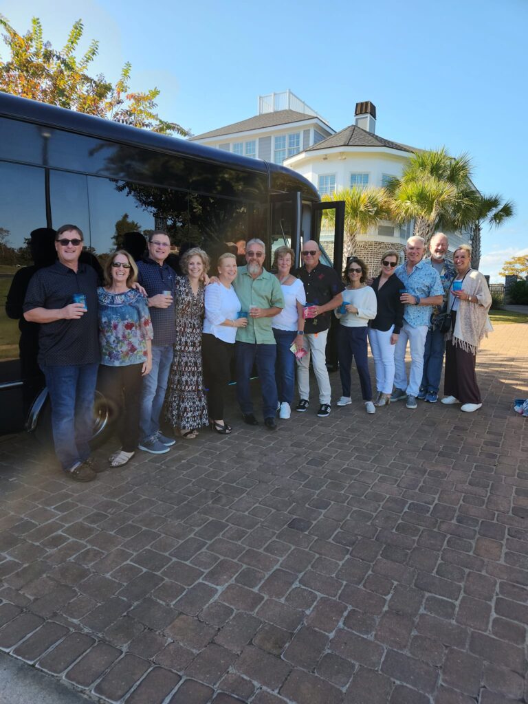 Group of people posing by a black executive car service in Charleston.