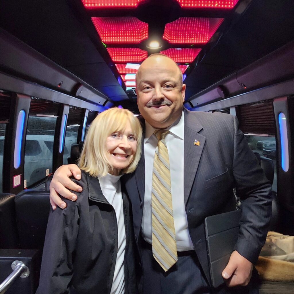 Man and woman posing inside a party bus with red accent lighting