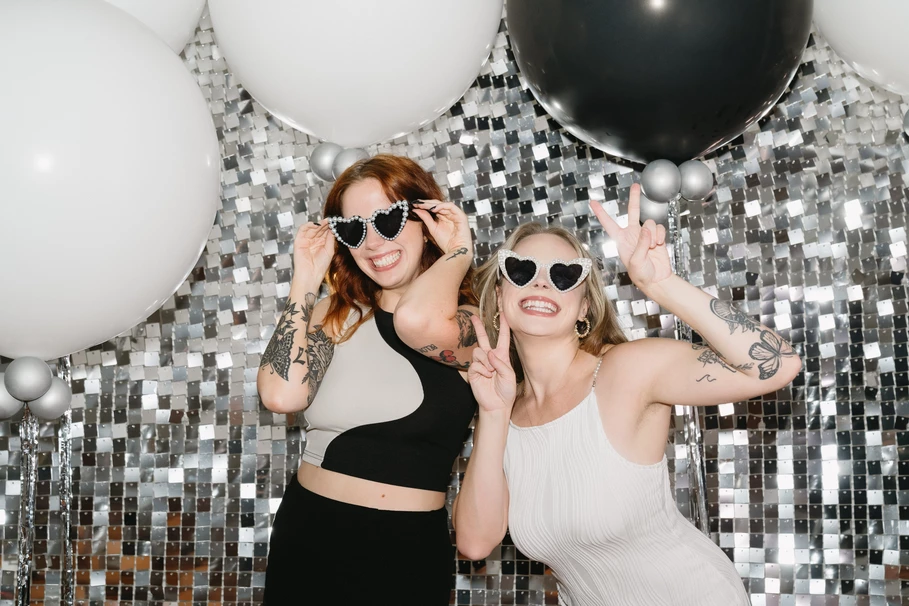 Two women pose with heart-shaped sunglasses at a photo booth event in Myrtle Beach.