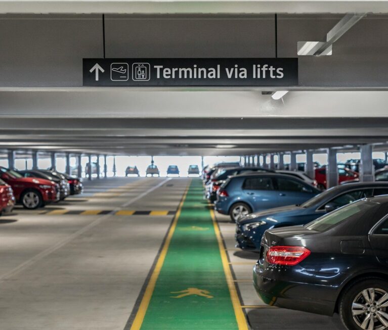 Cars parked in a multi-level parking garage with directional signage.