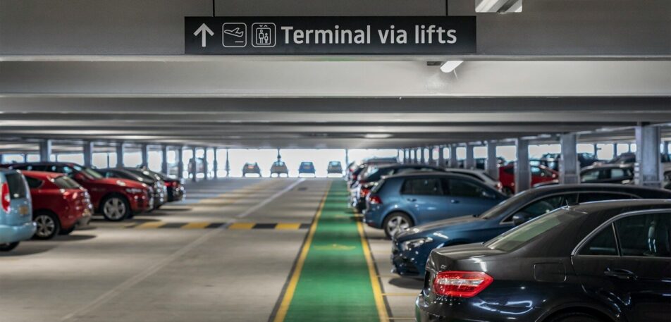 Cars parked in a multi-level parking garage with directional signage.