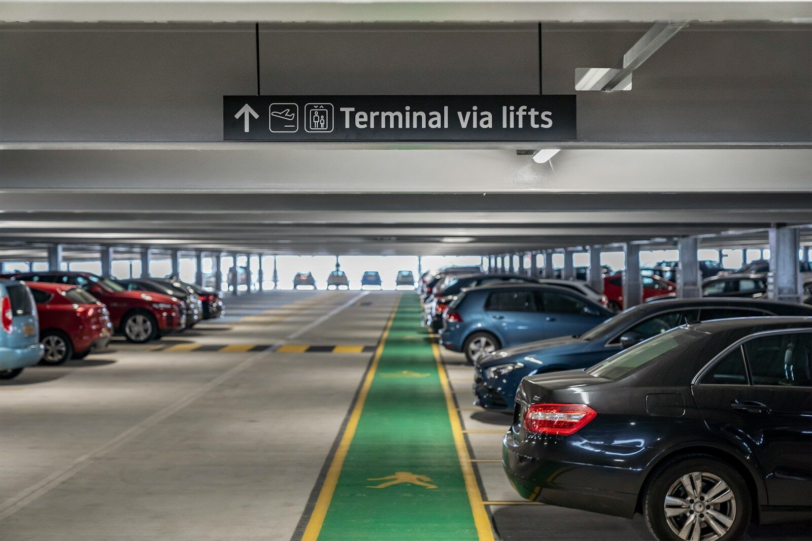 Cars parked in a multi-level parking garage with directional signage.