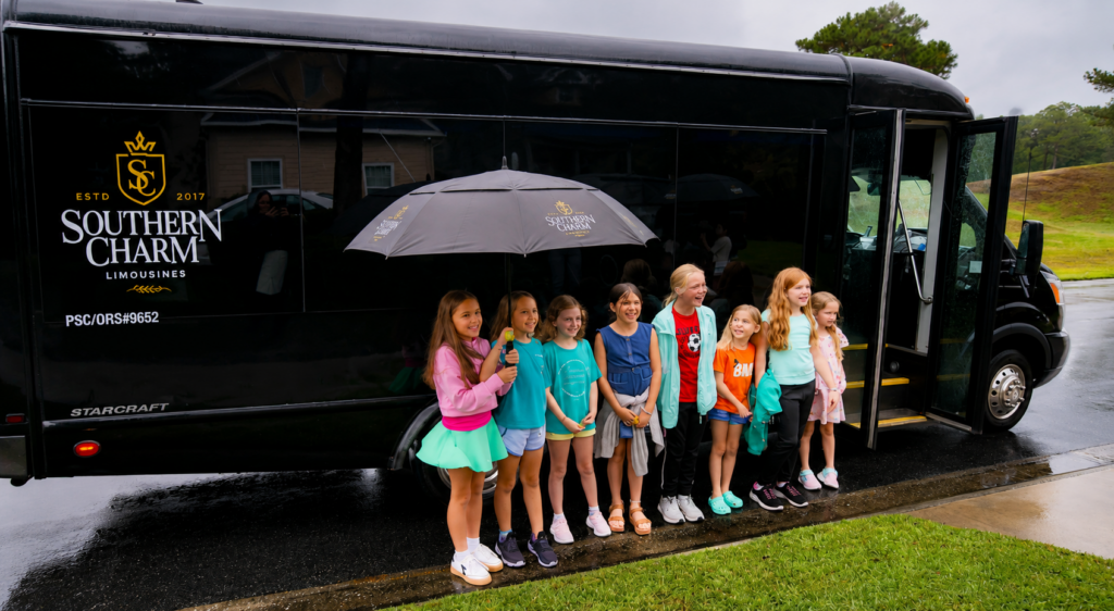 Kids birthday party bus with smiling children posing in front of Southern Charm Limousines